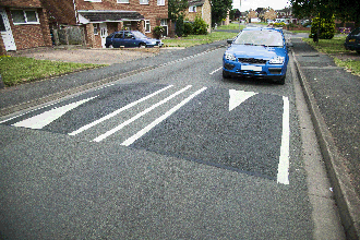 Safety margins - You're driving in a built-up area that has traffic-calming measures. What should you do when you approach a road hump?