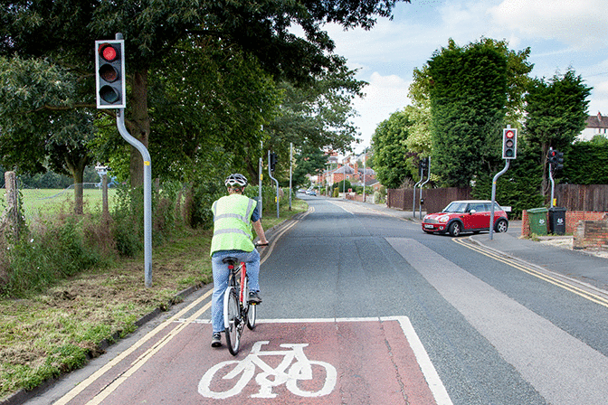 Hazard awareness - You're behind this cyclist. When the traffic lights change, what should you do?