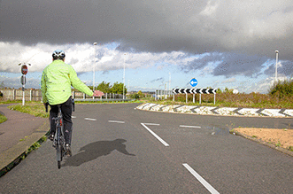 Vulnerable road users - You're approaching this roundabout. What should you do when a cyclist is keeping to the left while signalling to turn right?